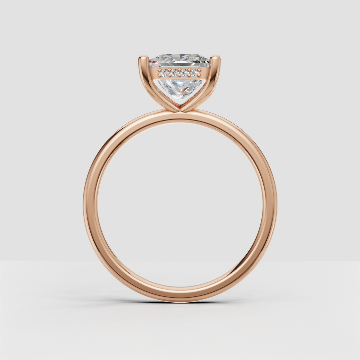 Princess cut diamond solitaire ring with four gold prongs and delicate accent stones beneath center
