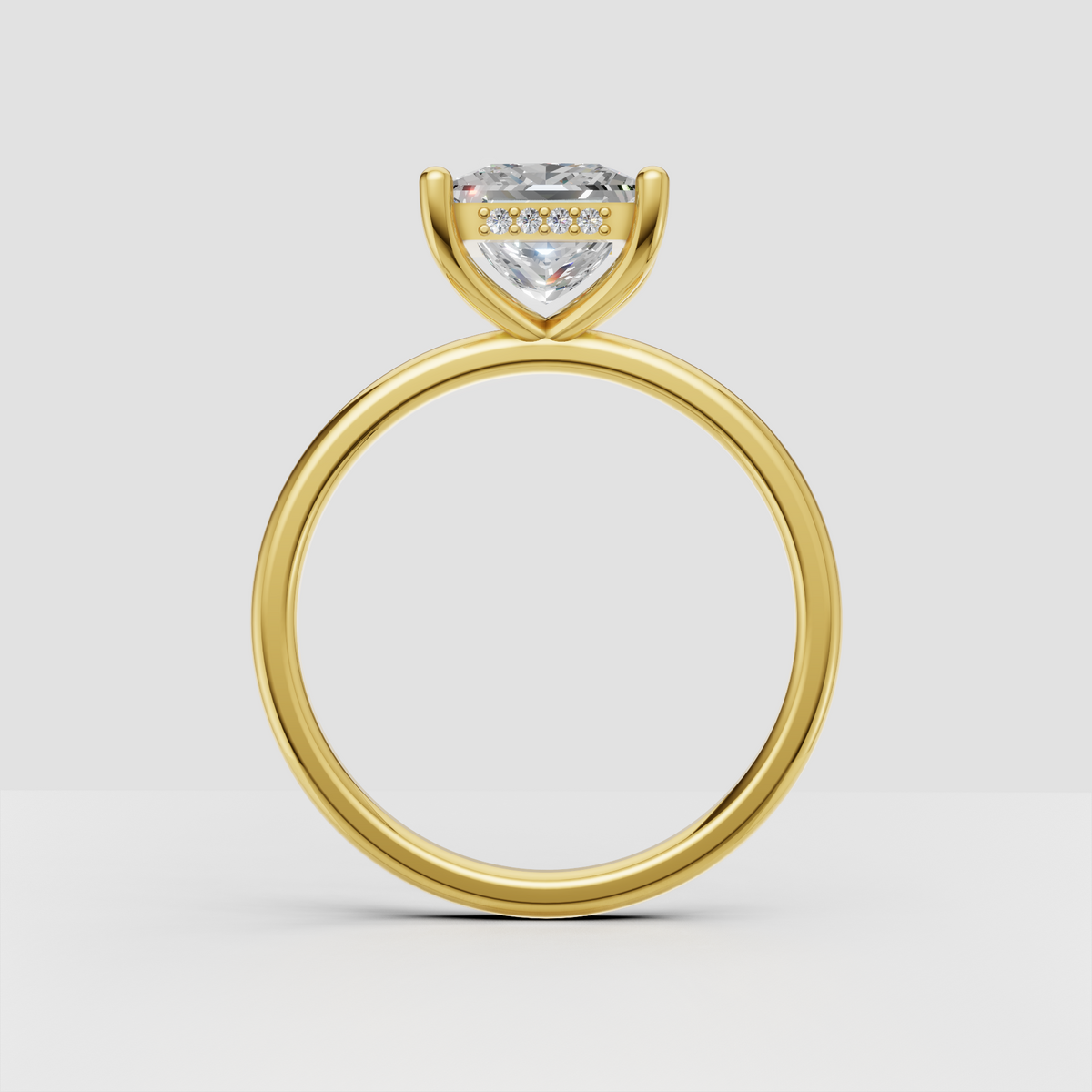 Close-up of princess cut diamond solitaire ring with polished gold band and four rounded prongs