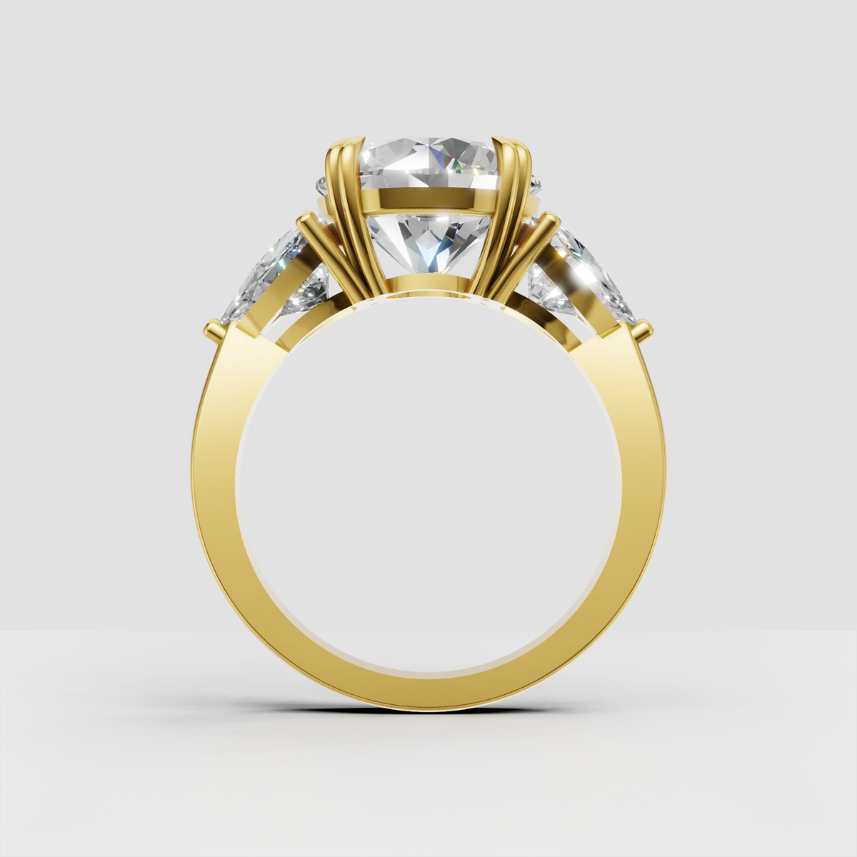 Round center diamond ring featuring pear shaped side diamonds and polished gold band