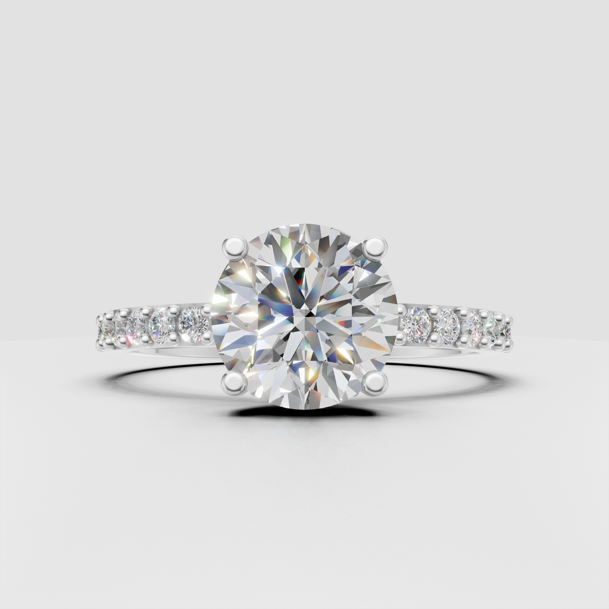 Four-prong round diamond ring featuring pavé-style diamond shoulders
