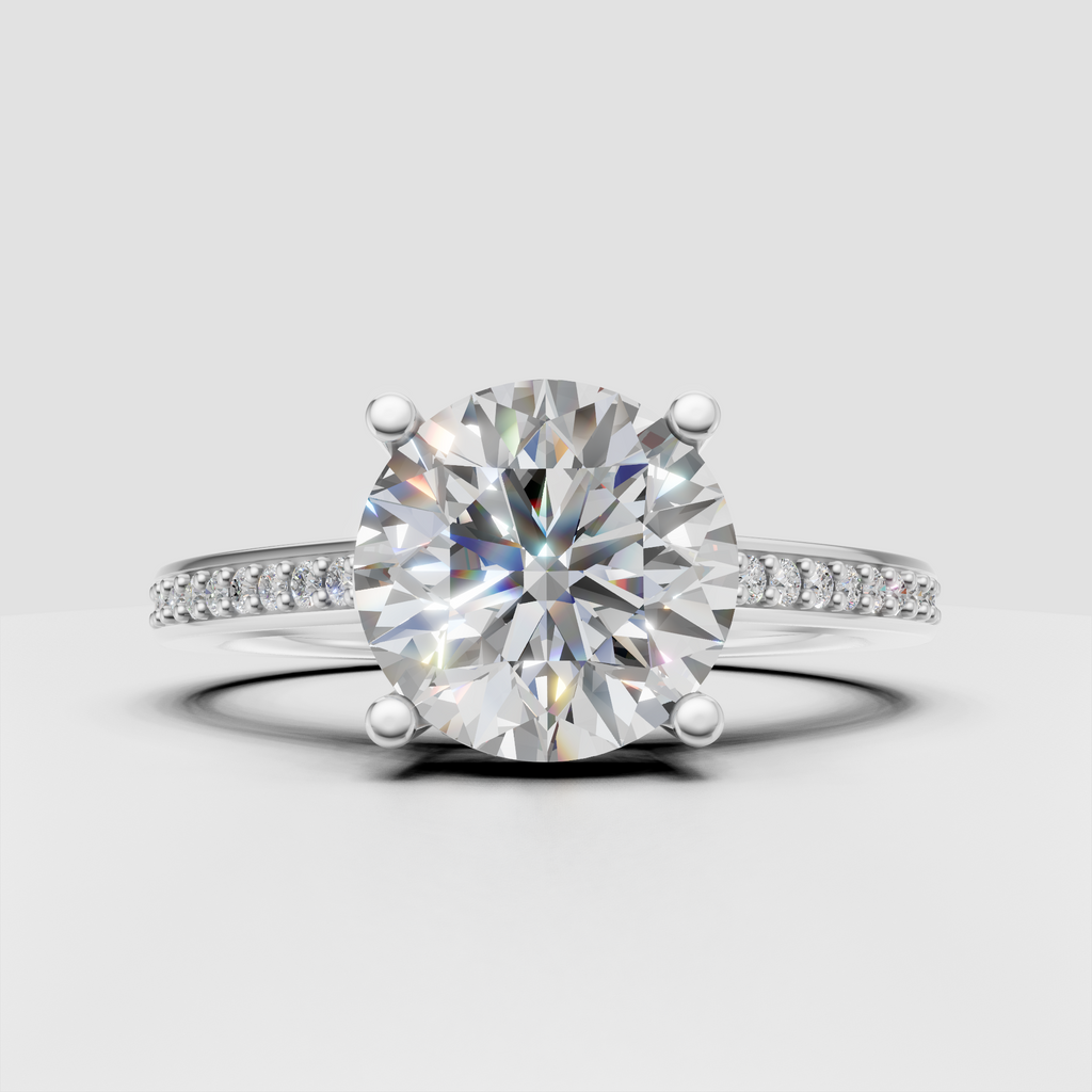 Four-prong round diamond ring with delicate pave-set shoulders.