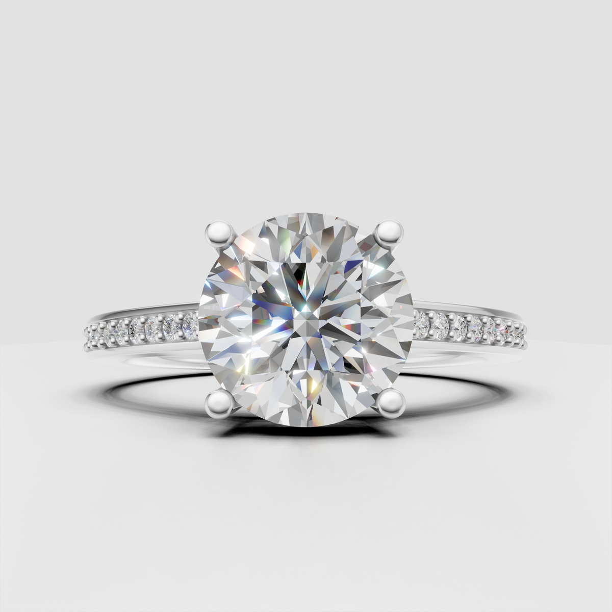 Four-prong round diamond ring with delicate pave-set shoulders.