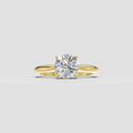 Round cut diamond solitaire ring with four prong setting and polished yellow gold band