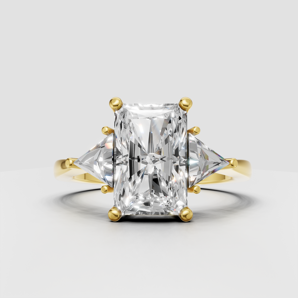 Radiant diamond three-stone engagement ring with trillion side stones in yellow gold