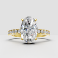 Pear cut diamond cathedral engagement ring in polished yellow gold with pavé band