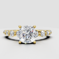 Cushion diamond four-prong engagement ring with pavé side stones in yellow gold