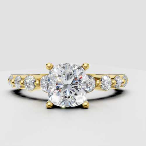 Cushion diamond four-prong engagement ring with pavé side stones in yellow gold