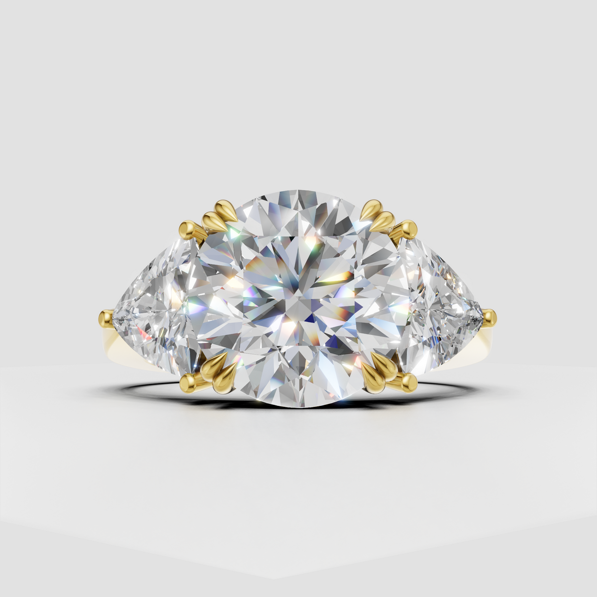 Round cut diamond three stone engagement ring with pear shaped side accents in yellow gold