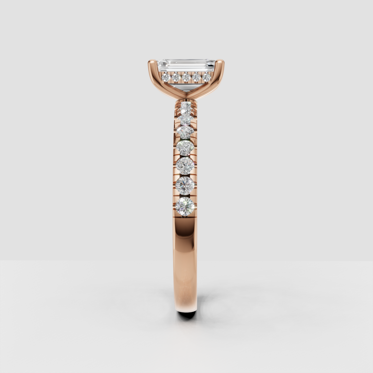 Emerald cut engagement ring featuring four rounded prongs and diamond-set shoulders