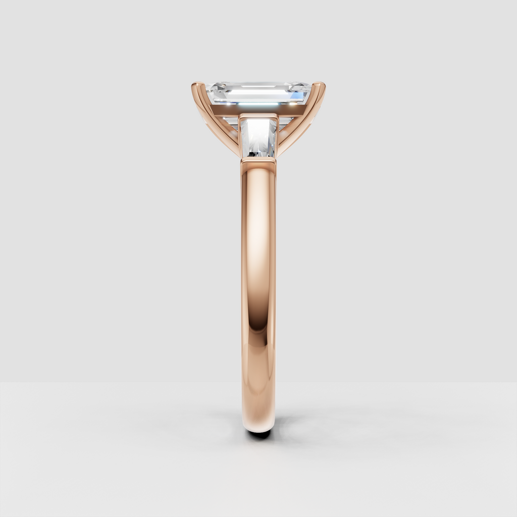 Four-prong emerald cut diamond ring with tapered side stones in yellow gold