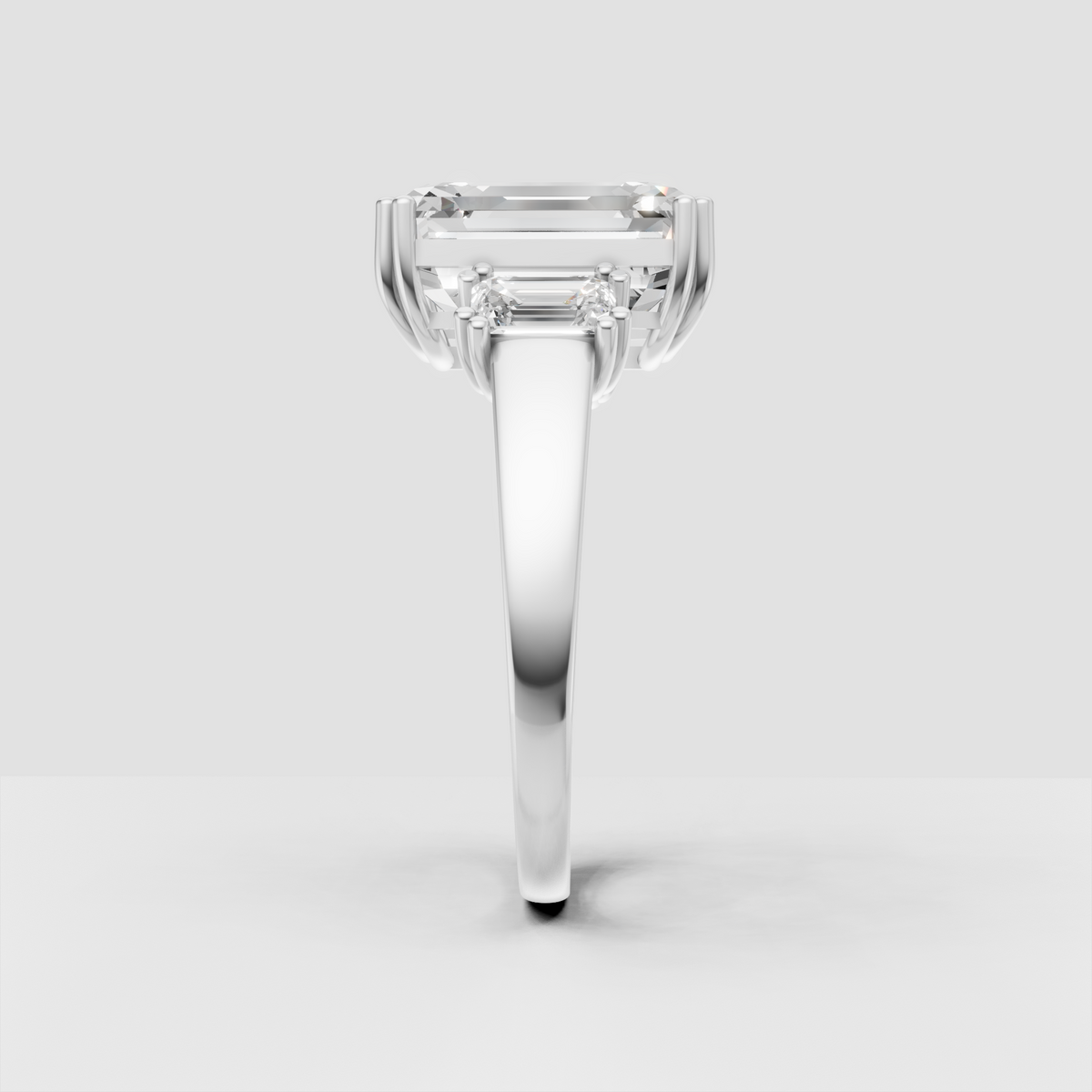 Elongated emerald cut diamond with two side stones