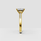 Elongated emerald cut center stone in a four-prong gold setting.