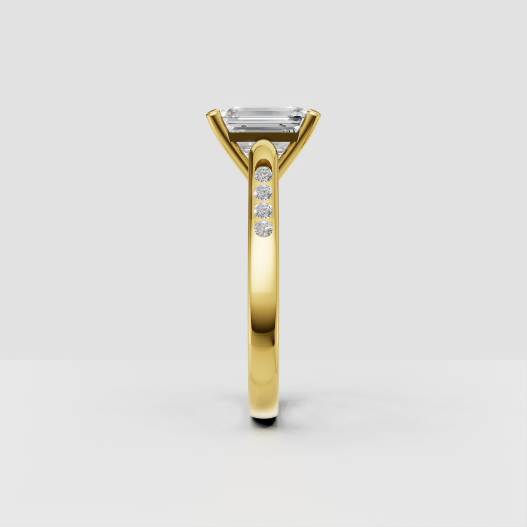 Elongated emerald cut center stone in a four-prong gold setting.