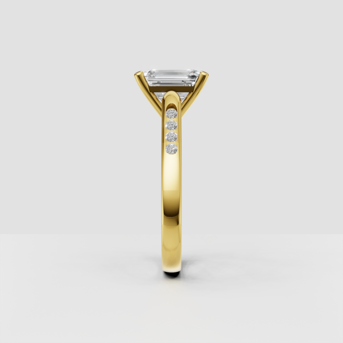 Elongated emerald cut center stone in a four-prong gold setting.